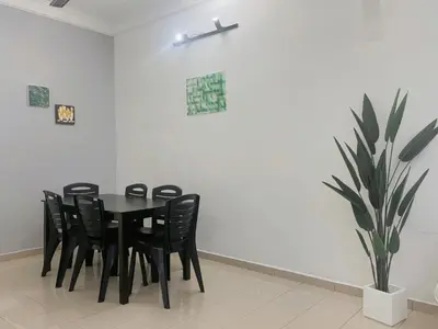 a black dining room table with black chairs and a plant at Homestay 2 @Taman Teluk Intan in Teluk Intan
