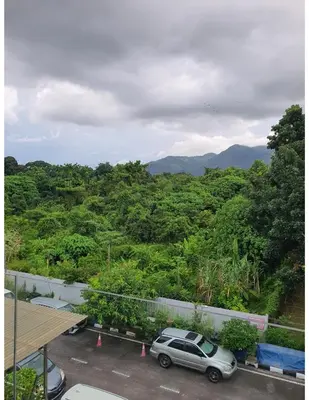 a car parked in a parking lot with mountains in the background at Homestay Pohon Rendang in Balik Pulau