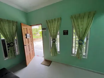 a green room with a door and two windows at Rumah Comel in Kampung Degong