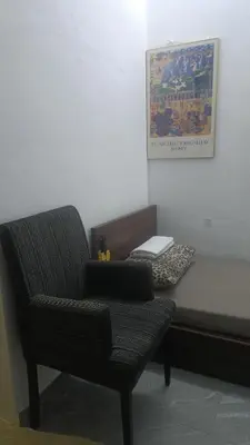 a chair sitting next to a bed with a laptop at Mini Studio in Permatang Pauh