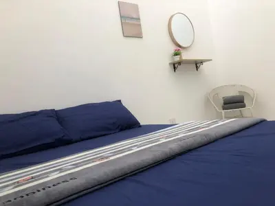 a bed with blue sheets and a chair in a room at Al Ghazali Homestay in Seri Iskandar