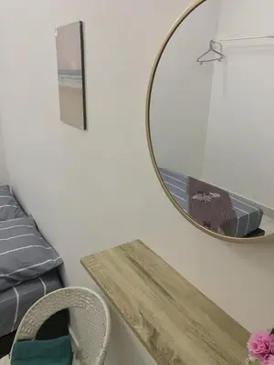 a mirror on a wall next to a bed and a table at Al Ghazali Homestay in Seri Iskandar