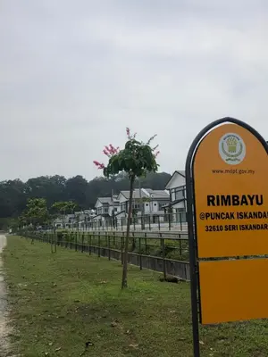a sign in a field with houses in the background at Al Ghazali Homestay in Seri Iskandar