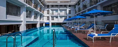 a swimming pool with blue chairs and umbrellas at Royale Chulan Penang in George Town