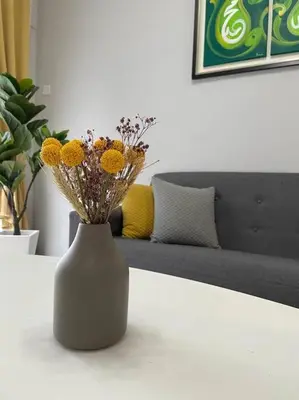 a white vase with yellow flowers on a table at Hanna Homestay Apartment for Muslim in Tanah Rata