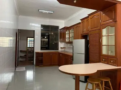 a kitchen with wooden cabinets and a table and a refrigerator at Pangkor Island Seaside @ 4 rooms Homestay in Pasir Bogak