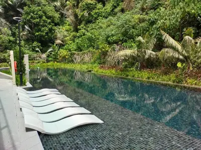 a row of white lounge chairs next to a swimming pool at be.Bamboo The Cove-6mins Lost World Tambun-10pax in Ipoh