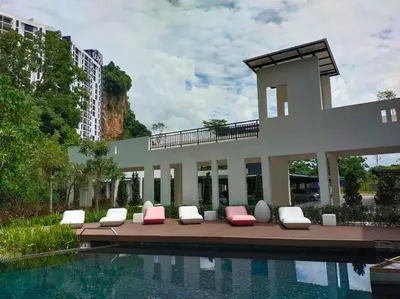 a building with lounge chairs next to a swimming pool at be.Bliss-8mins Lost World Tambun-6-7pax in Ipoh