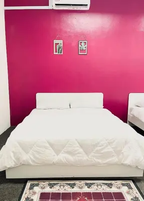 a bedroom with a white bed with a pink wall at AK Greenrise Meru in Ipoh