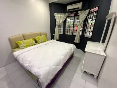 a small bedroom with a white bed with yellow pillows at Manjung Cozy Homestay in Sitiawan