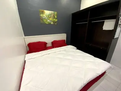 a white bed with red pillows in a bedroom at Manjung Cozy Homestay in Sitiawan