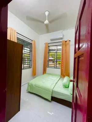 a bedroom with a green bed and a window at Tok Abah Homestay Bukit Mertajam in Bukit Mertajam