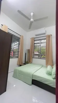 a bedroom with a green bed and a window at Tok Abah Homestay Bukit Mertajam in Bukit Mertajam