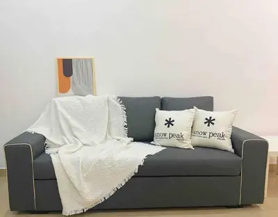 a gray couch with pillows and a blanket on it at Warm and Cozy in Teluk Intan