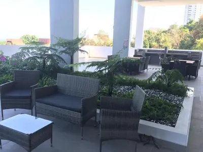 a patio with wicker chairs and tables and plants at New! Batu Ferringhi Seaview Cozy Condo, Penang in Batu Ferringhi