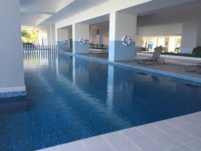 a swimming pool with blue water in a building at New! Batu Ferringhi Seaview Cozy Condo, Penang in Batu Ferringhi