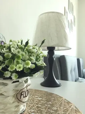 a table with a lamp and a vase of flowers at New! Batu Ferringhi Seaview Cozy Condo, Penang in Batu Ferringhi