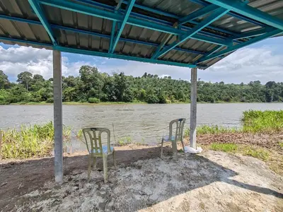 two chairs sitting under a pavilion next to a river at Homestay Tepi Sungai Perak in Kuala Kangsar