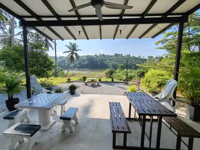 a patio with a table and benches and a view at Homestay Tepi Sungai Perak in Kuala Kangsar