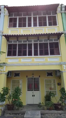 a yellow building with windows and plants in front of it at Shophouse Studio in George Town