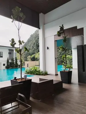 a lobby with two potted trees and a pool at Sunway Onsen Suites beautiful view in Kampong Batu Lapan