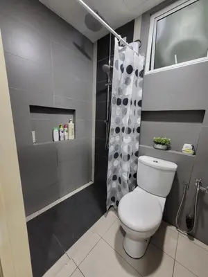 a bathroom with a white toilet and a shower at NICE and COZY studio apartment with gym and pool. in Kampar
