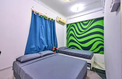 a room with two beds and a green wall at Penang Dream Banglo Sleeps 65 in Tanjung Bungah