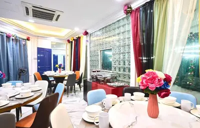 a restaurant with tables and chairs and a vase of flowers at Penang Dream Banglo Sleeps 22 in Tanjung Bungah