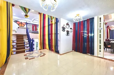 a room with colorful curtains on the walls and a dining room at Penang Dream Banglo Sleeps 18 in Tanjung Bungah