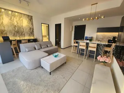 a living room with a white couch and a kitchen at Urban Suite - George Town in Jelutong