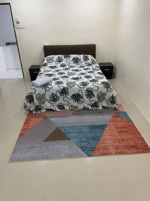 a bedroom with a bed with colorful rugs on the floor at SunShine HomeStay in Bukit Mertajam