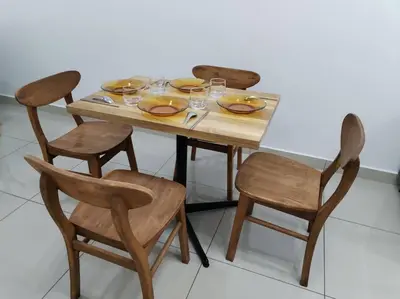 a wooden table and chairs with plates and wine glasses at Nana's Sitiawan Home Stay, Victoria cottage in Sitiawan