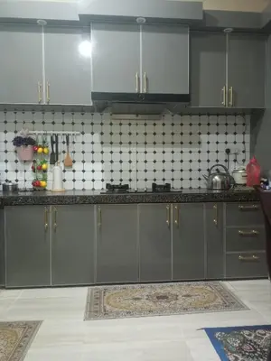 a kitchen with gray cabinets and a tile wall at Cp homestay in Batu Kurau