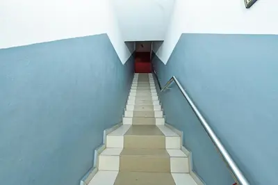 a staircase with a red door in a blue building at Hotel O M Three Hotel in Kampong Batu Tiga