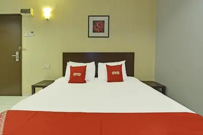 a large bed with two red pillows on it at Hotel O M Three Hotel in Kampong Batu Tiga