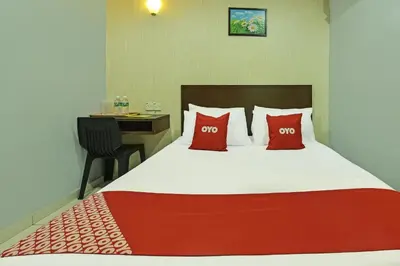 a bedroom with a bed with red pillows and a desk at Hotel O M Three Hotel in Kampong Batu Tiga