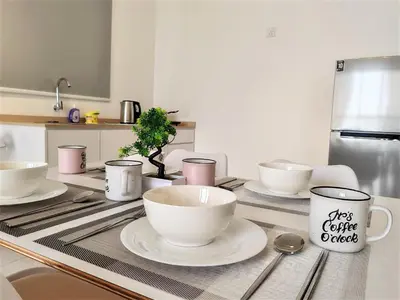 a kitchen with white cups and plates on a counter at Cozy Minimalist Suite at Urban Suites Georgetown by SuperStay in Jelutong