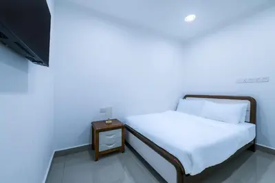 a bedroom with a bed with a night stand and a tv at Capital O 90543 Sp Star Hotel in Sungai Petani
