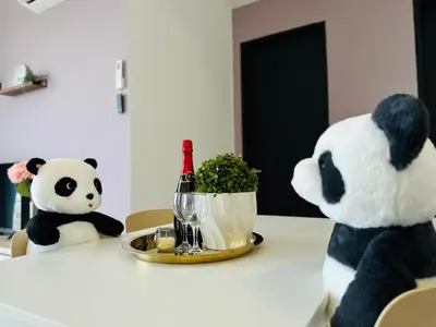 two stuffed pandas sitting at a table with a bottle of wine at New Comfy Urban Suite Homestay at Georgetown for family by Urban Staycations LOD COSY in Jelutong