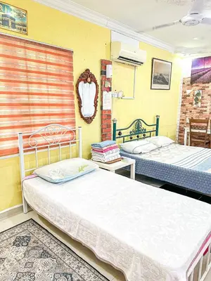 two beds in a room with yellow walls at Dusun Indah Cottage 1 in Bayan Lepas