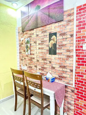 a table and two chairs with a table and a brick wall at Dusun Indah Cottage 1 in Bayan Lepas