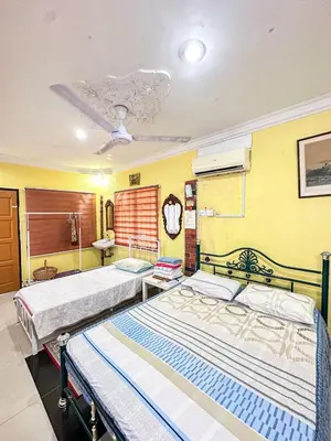 two beds in a room with yellow walls at Dusun Indah Cottage 1 in Bayan Lepas