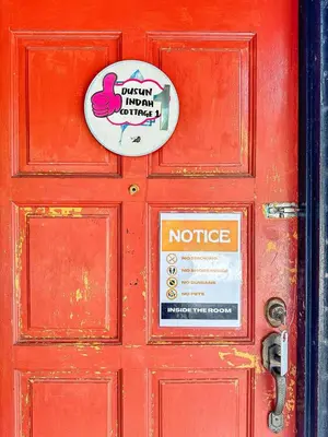 a red door with a sign on it at Dusun Indah Cottage 1 in Bayan Lepas