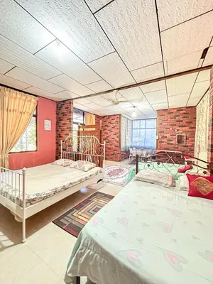 a bedroom with two beds and a brick wall at Dusun Indah Cottage 2 in Bayan Lepas