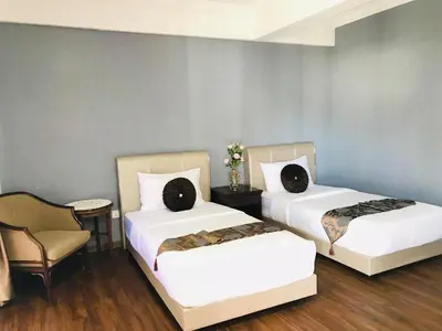 two beds in a room with a chair at Zaque's Hotel in Sungai Petani