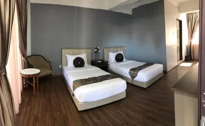a hotel room with two beds and a chair at Zaque's Hotel in Sungai Petani