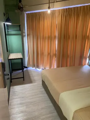 a bedroom with a bed and a window with a table at Clock Inn Backpackers Hostel in Tanah Rata