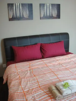 a bed with two red pillows and a black headboard at Batu Ferringhi - Shamrock Beach Villas, Penang in Batu Ferringhi