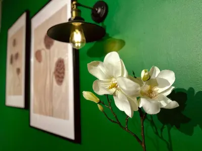 a vase with white flowers in front of a green wall at (New) Beachside Antique Villa@14 pax in George Town