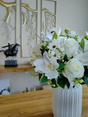 a white vase filled with white flowers on a table at FA House by the Beach in Tanjung Bungah